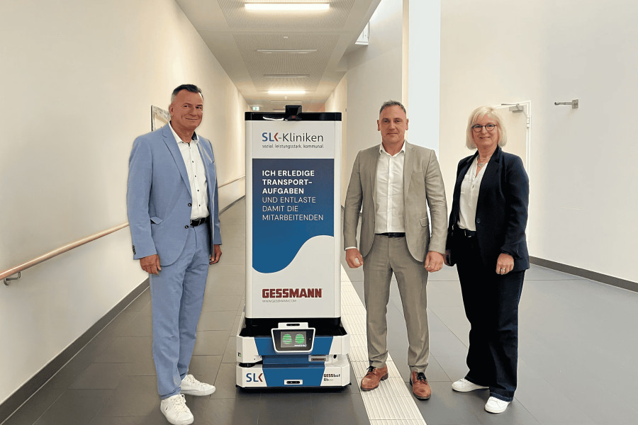 Von links: Alwin Ehrensperger (Geschäftsführer, W. Gessmann GmbH), Steffen Kuhnle (Leiter Geschäftsbereich Robotik, W. Gessmann GmbH) und Stephanie Haußmann (Geschäftsführerin, SLK-Service GmbH) präsentieren den „GESSbot“ im SLK-Klinikum Heilbronn. (Bildquelle: Heilbronner Stimme/KI-bearbeitet: W. Gessmann GmbH)