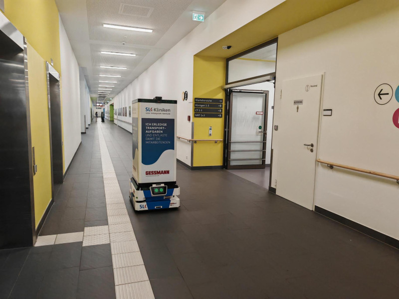 Der „GESSbot“ transportiert Medikamente autonom zwischen Zentralapotheke und Onkologie und unterstützt die innerklinische Logistik im laufenden Krankenhausbetrieb. (Bildquelle: Heilbronner Stimme/KI-bearbeitet: W. Gessmann GmbH)