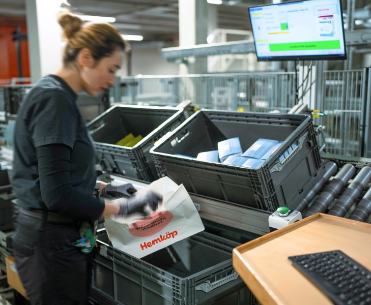 Die Kommissionierung der E-Commerce-Aufträge erfolgt in allen Temperaturbereichen an teilautomatisierten ergonomischen Arbeitsplätzen direkt in die Versand-Tasche. (Bildquelle: Witron)