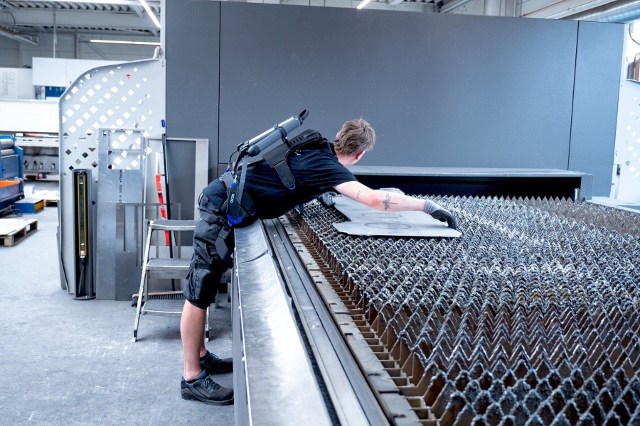 Mitarbeitende werden bei der Be- und Entladung von Metallbearbeitungsmaschinen durch das Rumpfbeuge-Exoskelett „Nexo Pro“ unterstützt und ihre Rückenbelastung reduziert. (Quelle: J. Schmalz GmbH)