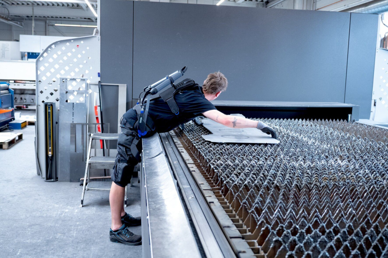 Mitarbeitende werden bei der Be- und Entladung von Metallbearbeitungsmaschinen durch das Rumpfbeuge-Exoskelett „Nexo Pro“ unterstützt und ihre Rückenbelastung reduziert. (Quelle: J. Schmalz GmbH)